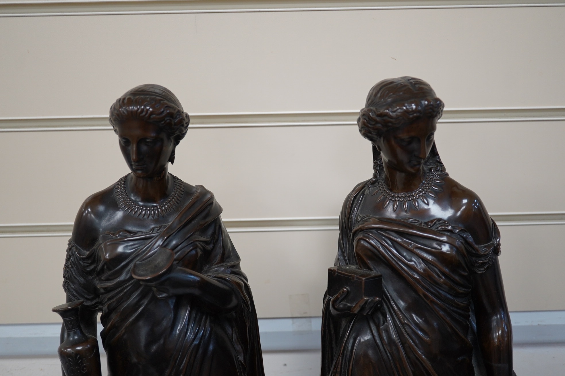 Eugene-Antoine Aizelin (French, 1820-1902). A pair of bronze classical robed figures of Pandora and Hebe, one holding a casket, the other a ewer and cup, having dark brown patination Height 50cm on square plinth base, si